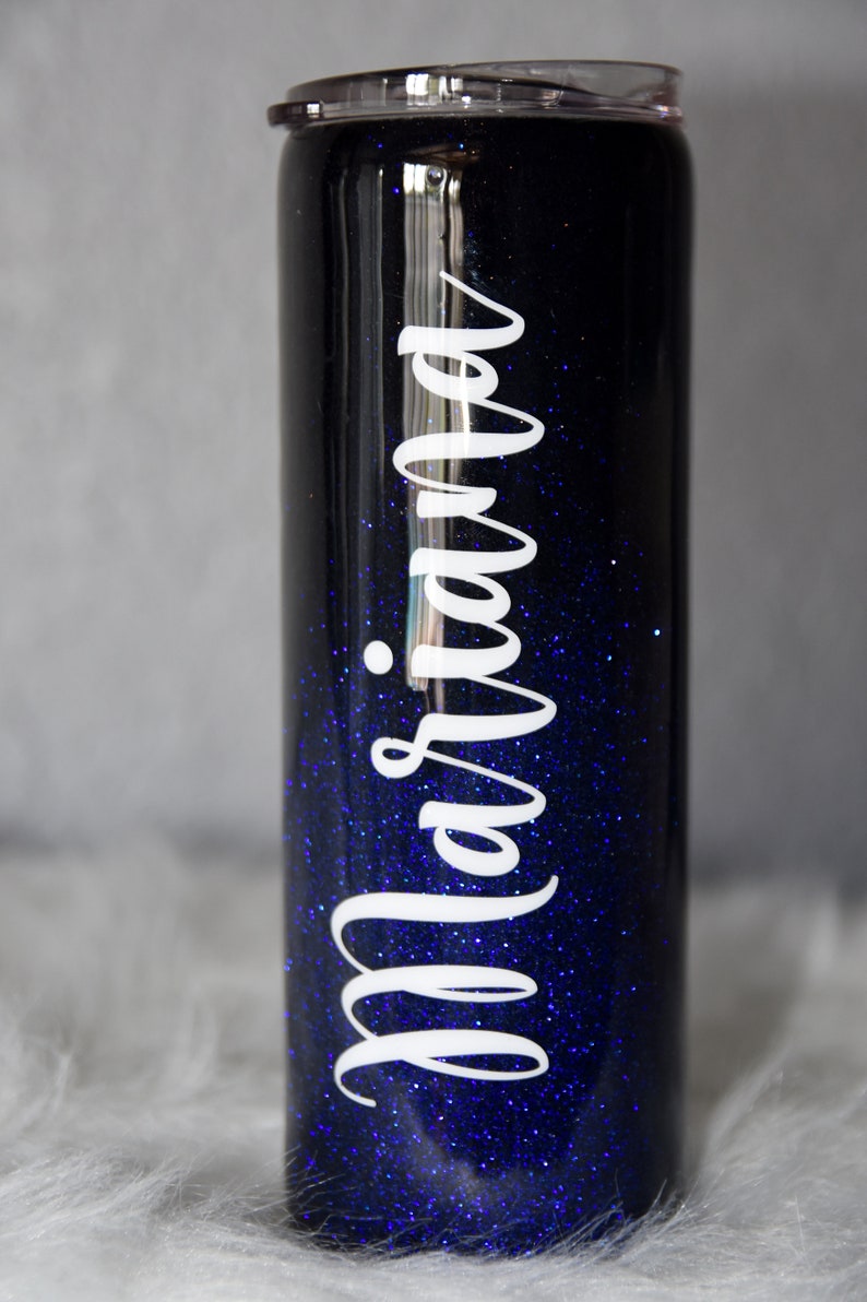 May include: A black and blue glitter tumbler with the name "Mariana" written in white on the side.