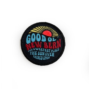 May include: A black and white embroidered patch with a red and yellow sun and the text "Good Ol' New Bern The Sweetest Place The Sun Ever Shined Upon."