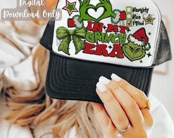 May include: A white and black trucker hat with a green Grinch design. The hat features a green bow, a red star, and the text "In My Grinch Era".