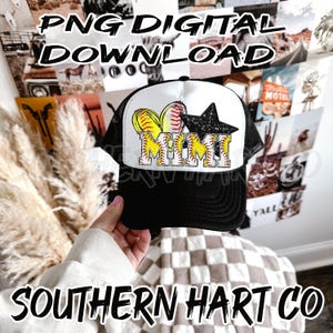 May include: Black and white trucker hat with a black star and yellow softball graphic. The hat says "Mimi" in yellow letters with a black outline.