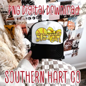 Puede incluir: Una gorra de camionero blanca y negra con una pelota de softball amarilla y un lazo con la palabra "Hermana" en puntadas de softball amarillas.