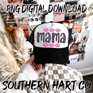 May include: White trucker hat with a black brim and a pink and blue geometric design that says "mama" in pink letters.