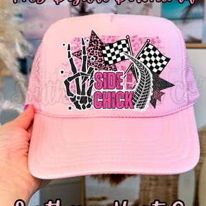 May include: Pink trucker hat with a mesh back and a curved peak. The front displays a graphic with a skeleton hand, stars, checkered flags, and the text "SIDE CHICK". The hat is a digital download.