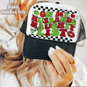 May include: A black and white trucker hat featuring a graphic with the text ON MY HUSBANDS NAUGHTY LISTS in red and green glittery letters. The design includes a black and white checkered border, a small red heart, and a red lip print.