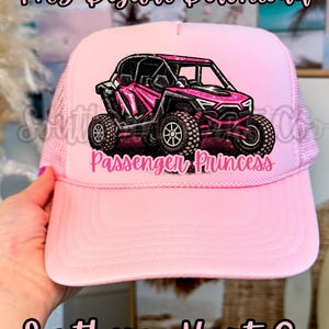 May include: Pink trucker hat with a pink and black off-road vehicle graphic and the text "Passenger Princess." The hat also features the text "PNG Digital Download" and "Southern Hart Co."