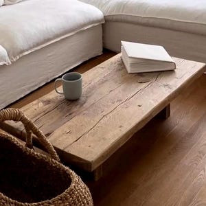 Può includere: Un tavolino rettangolare in legno chiaro con venature a vista. Una tazza grigia e un libro bianco chiuso sono sul tavolo. Un cestino intrecciato è in primo piano. Il tavolo misura circa 120 cm di lunghezza.