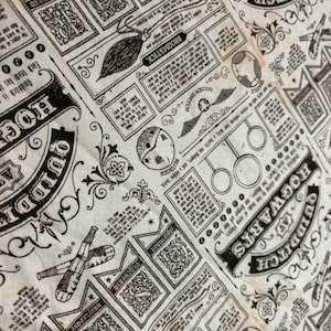 Puede incluir: Una tela de color crema con un estampado repetitivo en tinta negra de ilustraciones y texto con temática de Quidditch. El diseño incluye escobas, snitches doradas, bludgers, bates y escudos de casas con etiquetas como Hogwarts y Slytherin.