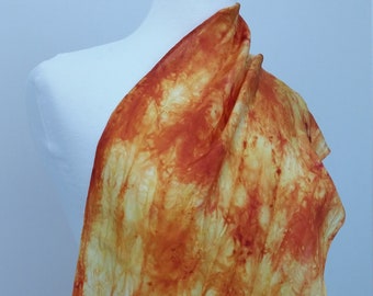 Może przedstawiać: Długi, zwiewny jedwabny szal w odcieniach pomarańczowego, żółtego i białego. Szal ma wzór tie-dye z subtelnym, abstrakcyjnym wzorem.