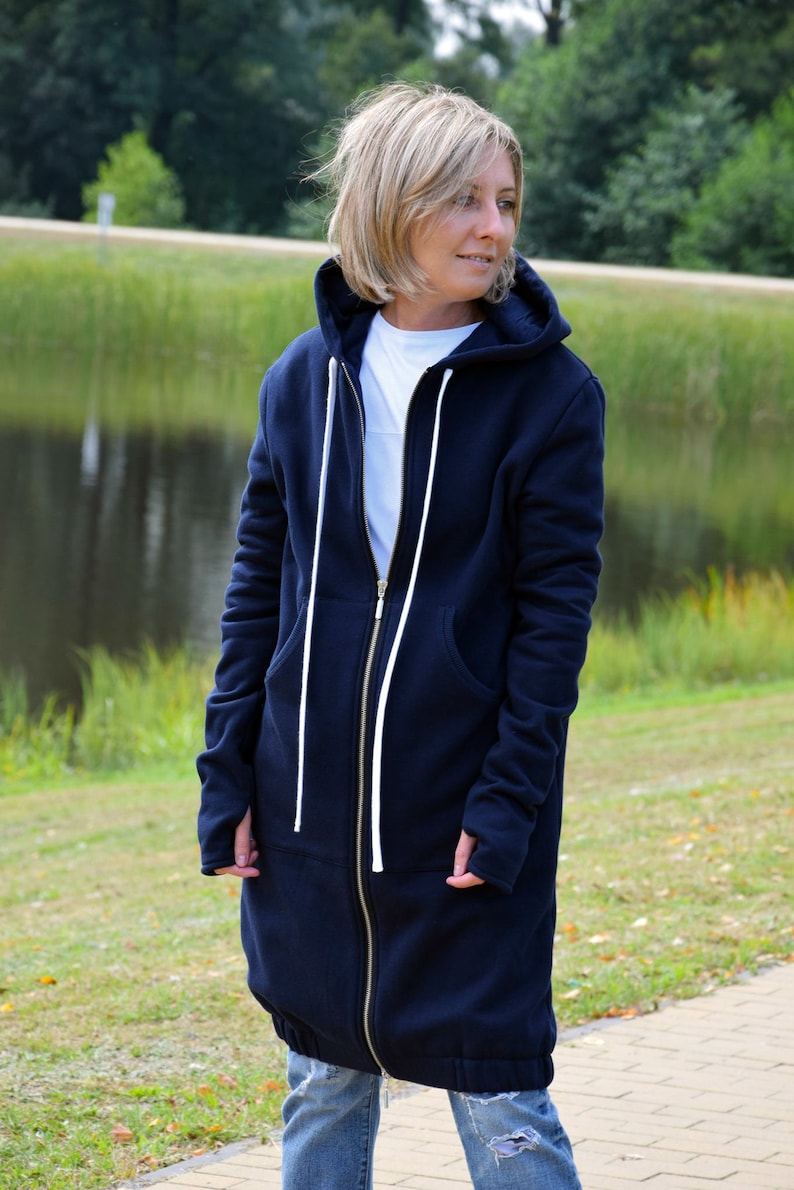May include: A long navy blue hooded sweatshirt with a zipper closure and white drawstrings. The sweatshirt has a relaxed fit and is made of a soft, comfortable fabric.
