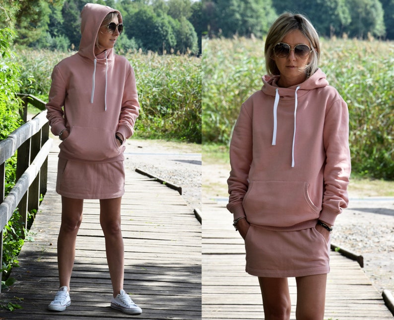 Pu&ograve; includere: Un set di felpa con cappuccio e gonna abbinata di colore rosa. La felpa ha un cappuccio con coulisse e una tasca a marsupio. La gonna &egrave; una minigonna con cintura.