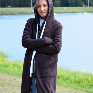 May include: A long brown hooded sweatshirt with a zipper closure and white drawstrings. The sweatshirt has a relaxed fit and is made of a soft, comfortable fabric.