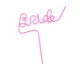 May include: A pink plastic straw with the word "BRIDE" in a decorative font. The straw is designed with a looped top and a straight bottom section, perfect for a bridal shower or bachelorette party.