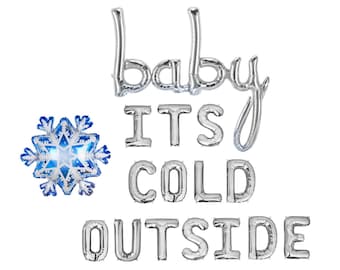 May include: Silver foil balloons spelling out the phrase baby ITS COLD OUTSIDE, arranged in four lines. To the left of the word baby, there is a single blue and white snowflake-shaped foil balloon with intricate geometric patterns.