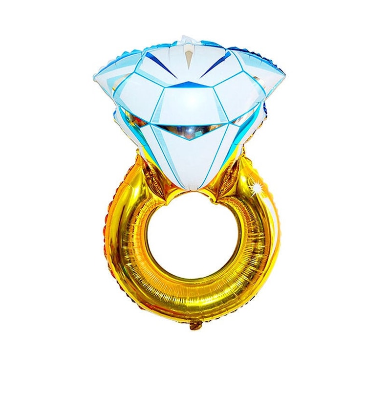 May include: A foil balloon shaped like a diamond ring. The band is metallic gold, and the large diamond setting is white with light blue geometric facets and accents. The balloon has a reflective, shiny surface and a circular opening in the center.
