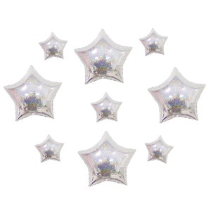 May include: A collection of eight star-shaped foil balloons in varying sizes. Each balloon features a translucent, iridescent finish with a holographic glitter effect that reflects light, creating a shimmering, multi-colored appearance.