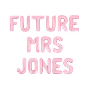 May include: Pink foil balloons spelling out "FUTURE MRS JONES" against a white background. The balloons are arranged in three lines, with "FUTURE" on top, "MRS" in the middle, and "JONES" at the bottom. Ideal for a bridal shower.