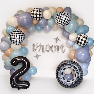 May include: A balloon arch in pastel colors, featuring checkered balloons, a black number 2 balloon, and a tire-shaped balloon. The word "vroom" is spelled out in silver balloons, with star accents. Perfect for a car-themed birthday.