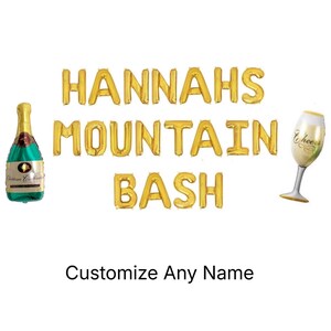 May include: Gold foil balloon letters spell "HANNAHS MOUNTAIN BASH" with a champagne bottle and a champagne glass balloon. The text "Customize Any Name" is below the balloon letters. Party decorations.
