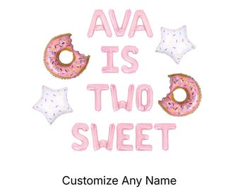 May include: A set of pink foil letter balloons spelling AVA IS TWO SWEET, accompanied by two round doughnut-shaped balloons with pink frosting and colourful sprinkles, and two white star-shaped balloons with colourful sprinkles. Text reads Customize Any Name.