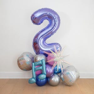 May include: A cluster of party balloons in shades of purple, silver, and blue. A large number 2 balloon is the focal point, complemented by disco ball and star-shaped balloons. A musical note balloon adds a unique touch.