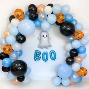 May include: A Halloween balloon arch with blue, white, orange, and black balloons. The arch is decorated with a ghost balloon and the word "BOO" in blue balloons.