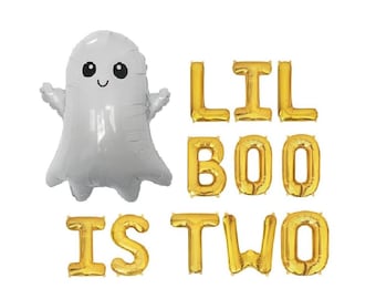 May include: A white ghost-shaped foil balloon with black eyes and a smile, accompanied by gold foil letter balloons that spell out the phrase LIL BOO IS TWO. The balloons are arranged in three rows against a plain white background.