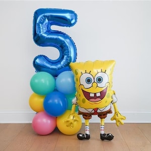May include: A balloon arrangement featuring a large, metallic blue number five balloon atop a cluster of round teal, yellow, blue, and pink balloons, positioned next to a yellow, rectangular Spongebob Squarepants character foil balloon.