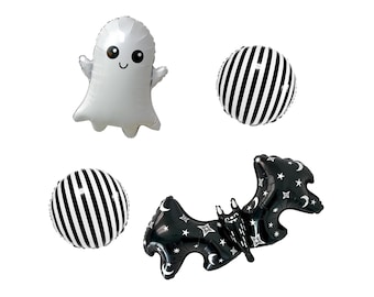 May include: A set of four foil balloons including a white ghost with a smiling face, two round balloons with vertical black and white stripes, and a black bat-shaped balloon decorated with white stars and crescent moon patterns.