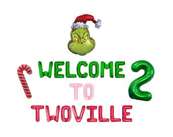 Op de afbeelding: Een set folieballonnen met een groen karakterhoofd met een rood-witte kerstmuts, een rood-witte zuurstok, een groot groen cijfer twee en letterballonnen die WELCOME TO TWOVILLE spellen in de kleuren groen, roze en rood.