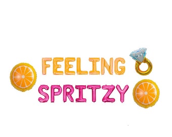 May include: A collection of foil balloons spelling "FEELING SPRITZY" in orange and pink. The balloons are accompanied by two orange slice balloons and a diamond ring balloon, perfect for a party or celebration.