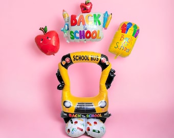 May include: A set of back to school themed balloons, including a yellow school bus shaped balloon with a frame, a red apple balloon, a balloon with the words "Back to School" and a balloon with a pencil holder and the words "Back to School".