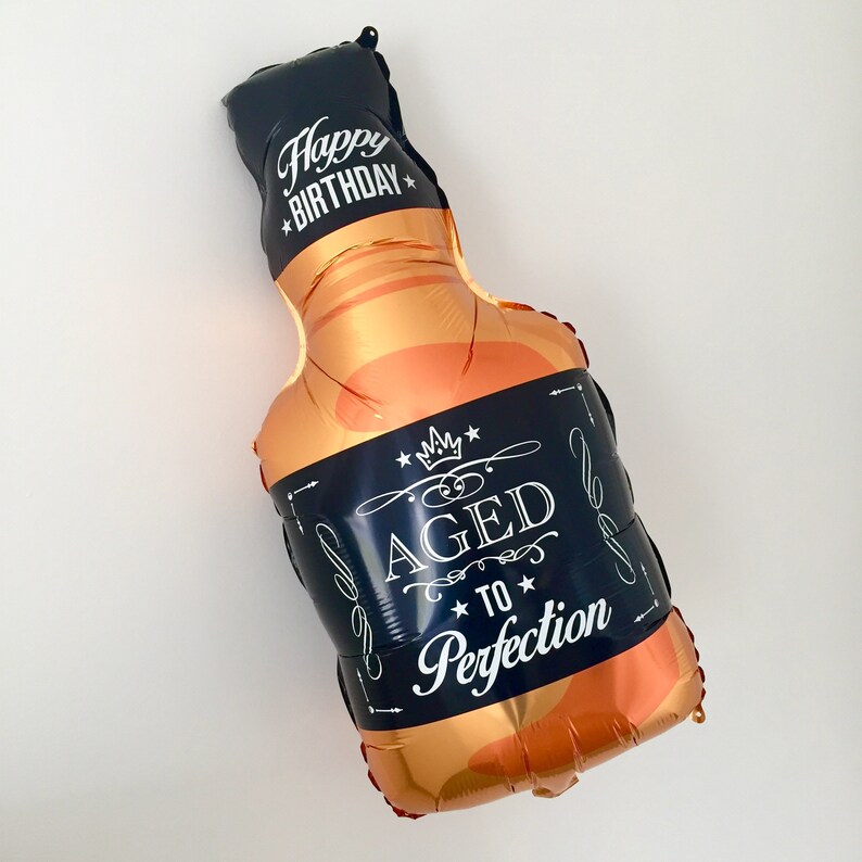 May include: A gold and black foil balloon shaped like a bottle of liquor with the text "Happy Birthday" and "Aged to Perfection" on the label.