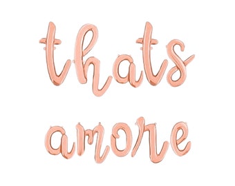 May include: Rose gold foil balloons spelling out "thats amore" in a cursive font. The balloons are inflated and ready for a party or celebration. The phrase is a romantic expression.