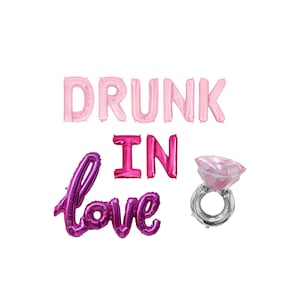May include: Pink and purple foil balloons spelling "DRUNK IN LOVE" with a pink diamond ring balloon.