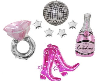 May include: A collection of foil balloons including a pink diamond ring, a silver disco ball, four small silver stars, a pair of bright pink cowboy boots, and a pink champagne bottle balloon with the text Celebrate and The Very Best printed on it.