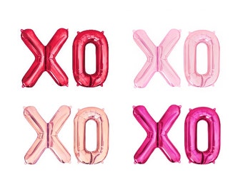 May include: Four sets of foil balloons shaped like the letters X and O, arranged in a grid. The colours include deep red, light pastel pink, metallic rose gold, and vibrant magenta. Each balloon has a reflective, metallic finish and smooth edges.