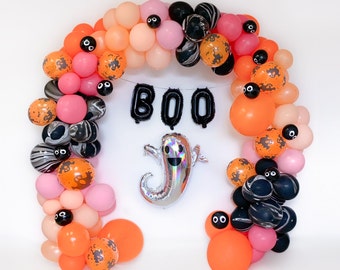 May include: A Halloween garland made of orange, black, and white balloons with the word "BOO" in black letters. The garland is decorated with black and white polka dot balloons and a silver ghost balloon.