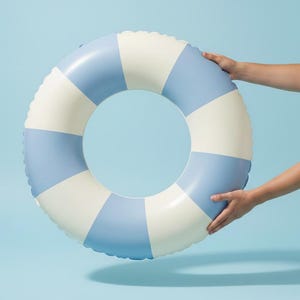 May include: A blue and white inflatable life ring. The life preserver is round with alternating sections of light blue and white. The image is set against a light blue background.