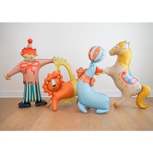 May include: A collection of circus-themed foil balloons. Includes a clown, a lion, a seal balancing a ball, and a horse. The balloons are brightly colored with details like stripes, patterns, and a yellow mane.