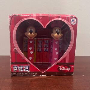 Puede incluir: Un set de regalo de caramelos PEZ con dispensadores de Mickey y Minnie Mouse. El empaque rojo tiene una ventana en forma de corazón, marca Disney y un peso neto total de 49,3g. Los dispensadores son amarillos, rojos y rosas con corazones.