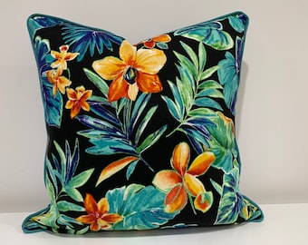 May include: A black pillow with a teal border features a tropical print with orange, yellow, and green flowers and leaves.