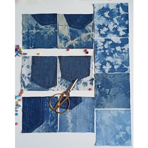 Può includere: Una collezione di nove quadrati di denim con diversi motivi di tintura a candeggina. I quadrati sono disposti a griglia su una superficie bianca. Un paio di forbici è sopra i quadrati.