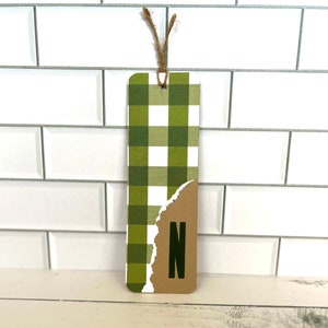Peut inclure: Signet de livre à carreaux verts et blancs avec un onglet en papier brun sur lequel est imprimée la lettre "N".