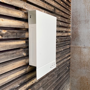 May include: White metal mailbox with the number 45B on a wooden wall.