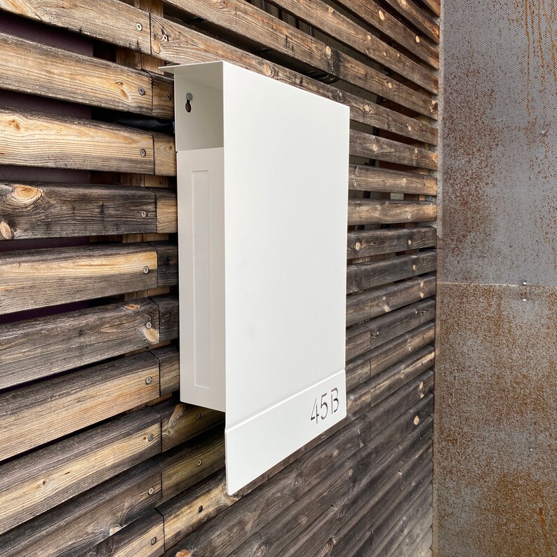 May include: White metal mailbox with the number 45B on a wooden wall.
