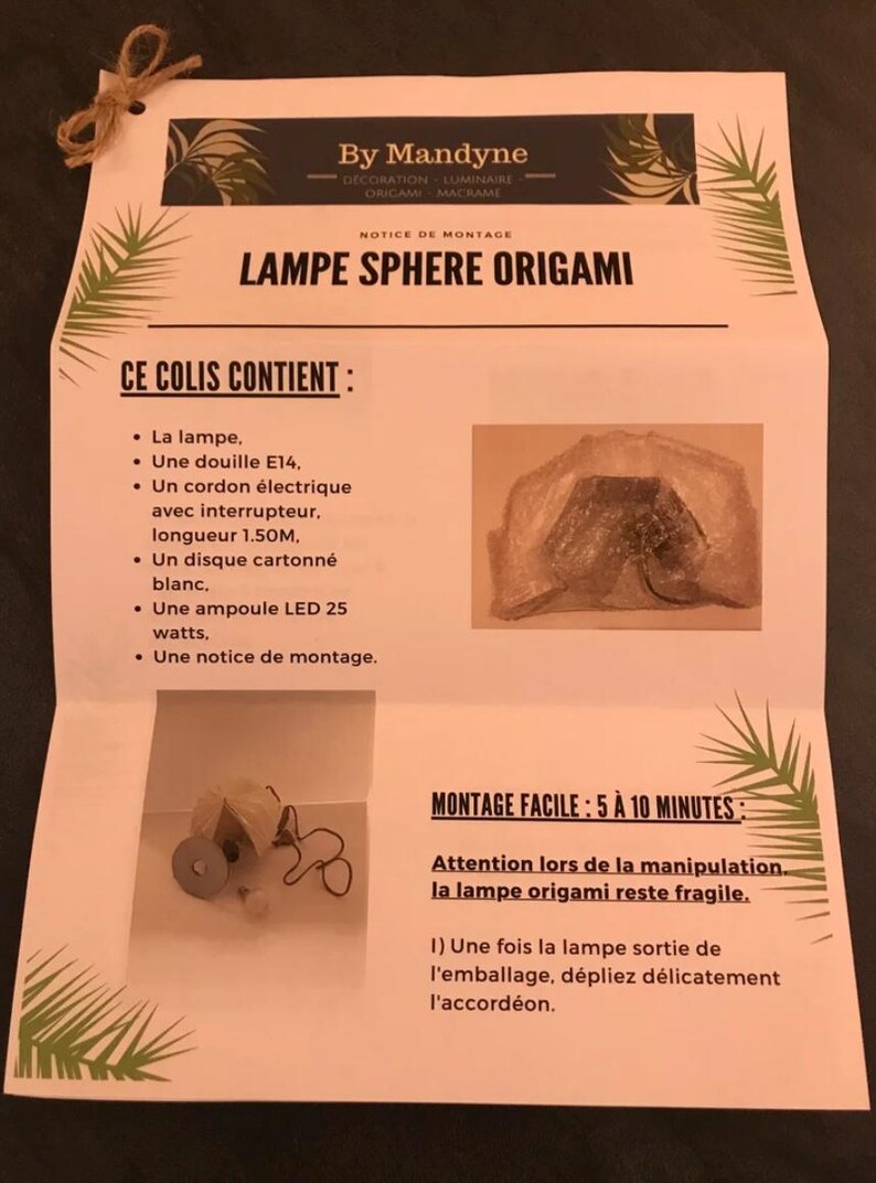 K&ouml;nnte beinhalten: Ein wei&szlig;es Anleitungsblatt f&uuml;r eine By Mandyne Origami-Kugellampe. Das Dokument enth&auml;lt Montageanweisungen und eine Inhaltsliste mit einer E14-Fassung, einem 1,50M langen Stromkabel mit Schalter, einer wei&szlig;en Pappscheibe und einer 25-Watt-LED-Lampe.