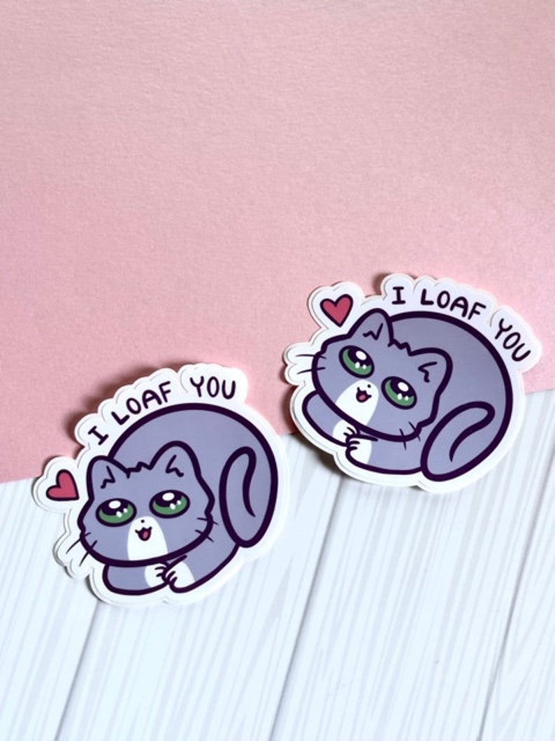 May include: Two stickers featuring a cartoon cat with the text "I LOAF YOU" and a heart. The cat is gray with white accents and is curled up in a loaf shape.