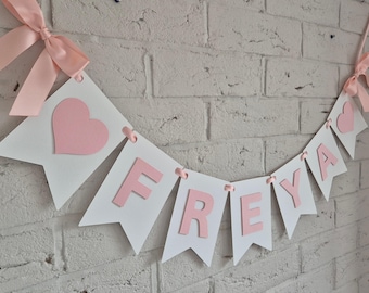 Roze en witte banner met naamslingers: decoraties voor de eerste verjaardag van een meisje
