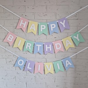Peut inclure: Banni&egrave;re de couleur pastel avec les mots "Happy Birthday Olivia" en lettres blanches.