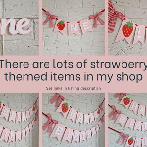 May include: Strawberry-themed birthday banner with pink and red felt letters and strawberry illustrations. The banner reads "Happy Birthday Lily".